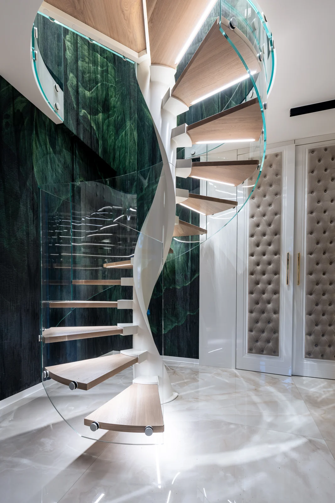 Spiral staircase with timber treads beside a green wall