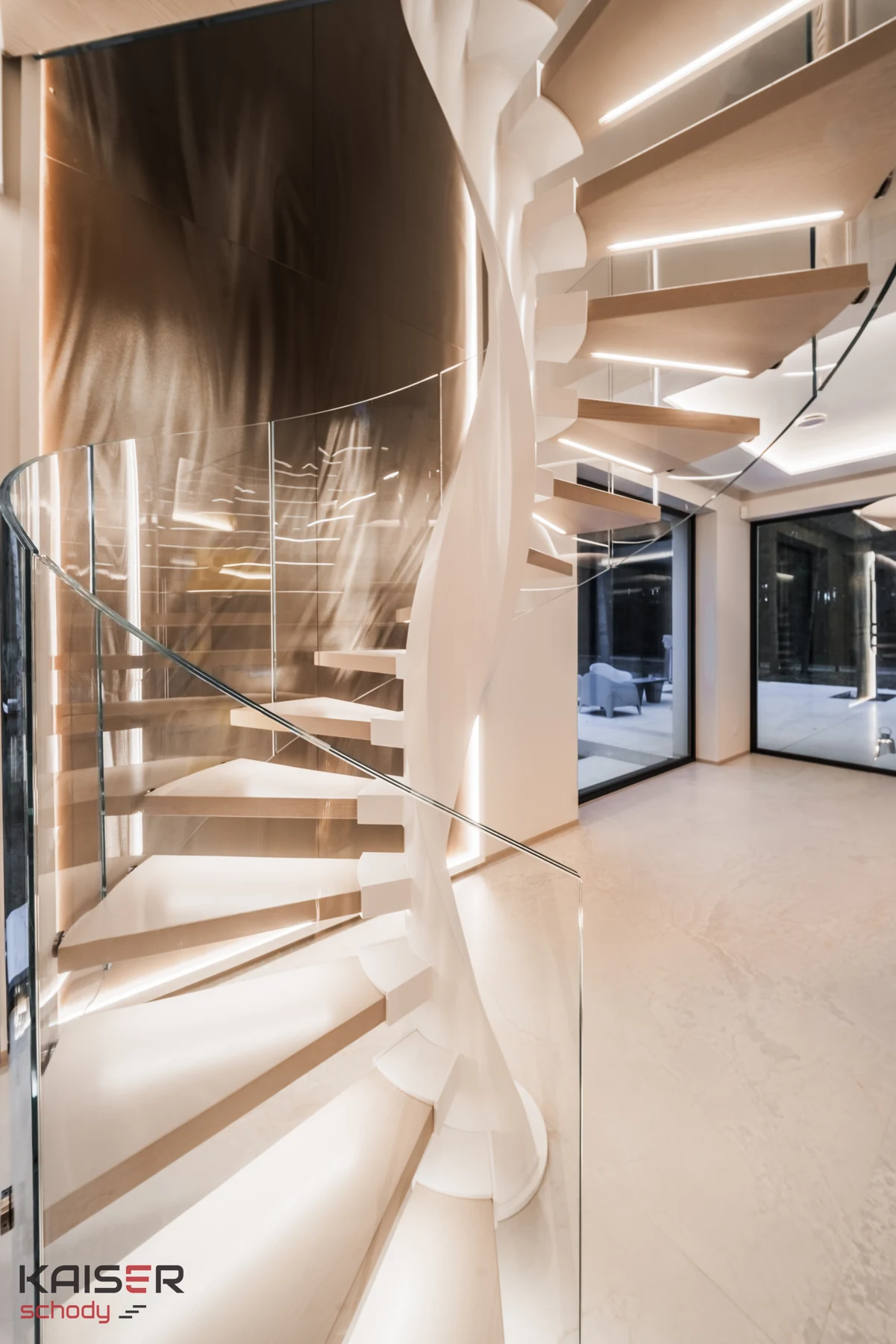 Light-coloured KAISER spiral staircase with lighting and a glass balustrade